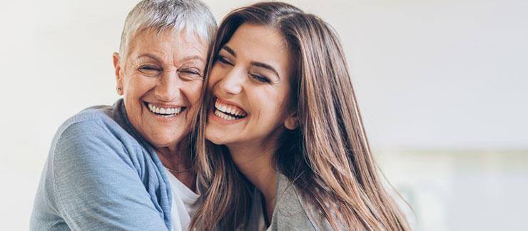 Senior woman smiles during a visit with daughter.