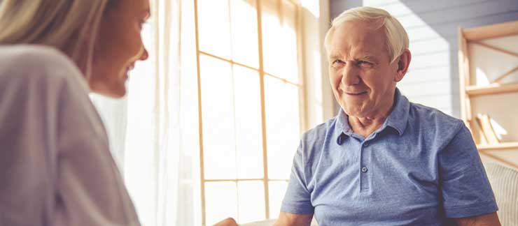 Female home care worker speaks to a senior man about home care services.