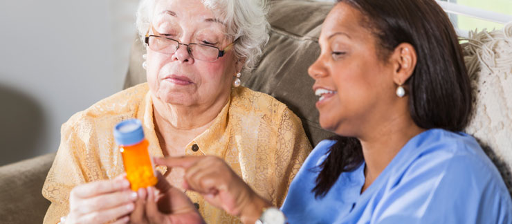 Caregiver explaining the medication reminder to a senior woman.