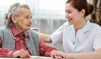 An elderly woman with dementia is comforted by a female home care worker.