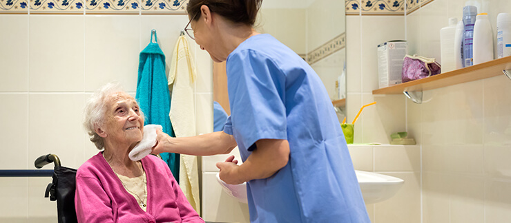 Caregiver providing hygiene services to an elderly woman.