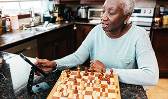 Senior woman playing chess with a friend on her mobile phone.