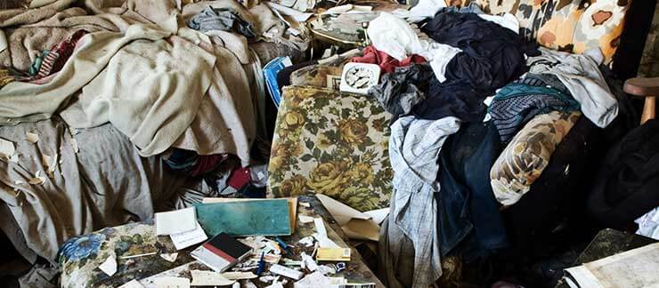 Piles of trash and dirty clothes clutter a room.
