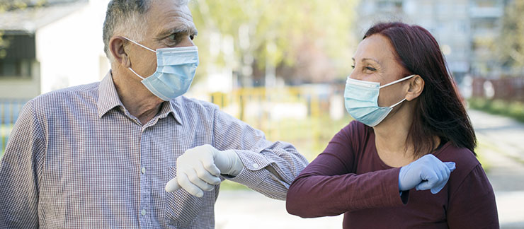 Two older adults communicate while wearing masks during COVID-19