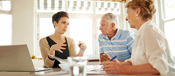 An in-home care provider speaking with a senior couple during a consultation.