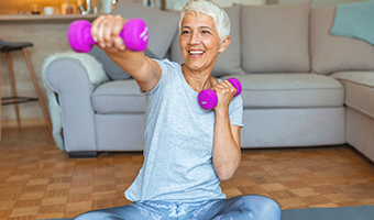 Senior woman exercises with hand weights in her home.