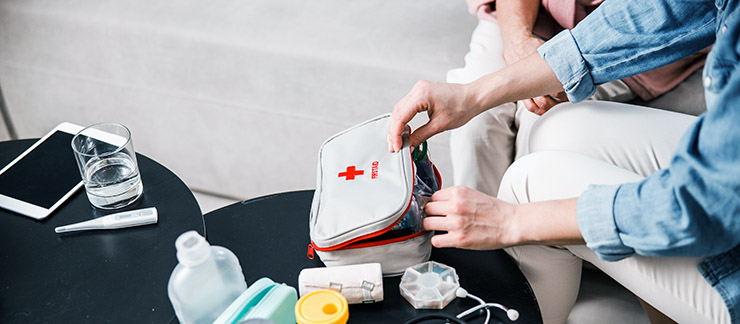 Close up of woman's hands checking supplies and items in a first aid kit in a senior's home.