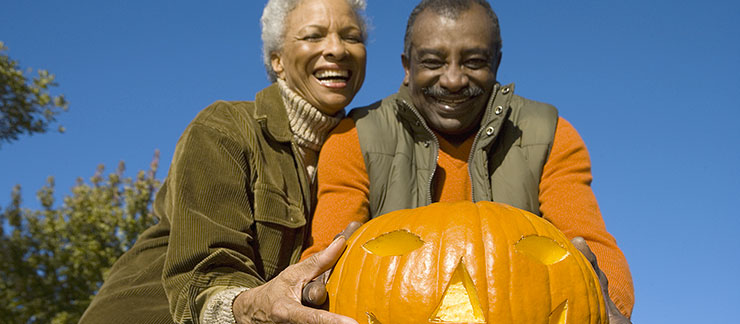 Senior couple displays their carved pumpkin outside during Halloween.
