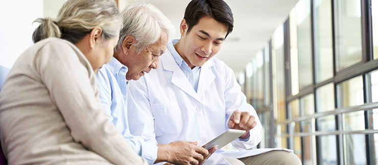 Senior couple receives hospital discharge instructions from a doctor using a computer tablet.