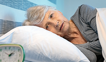 Worried senior woman in bed at night suffering from insomnia. 
