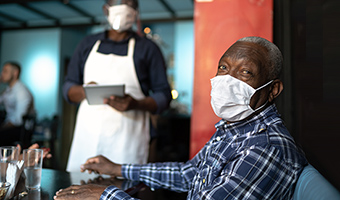 Senior with mask in restaurant during coronavirus pandemic.