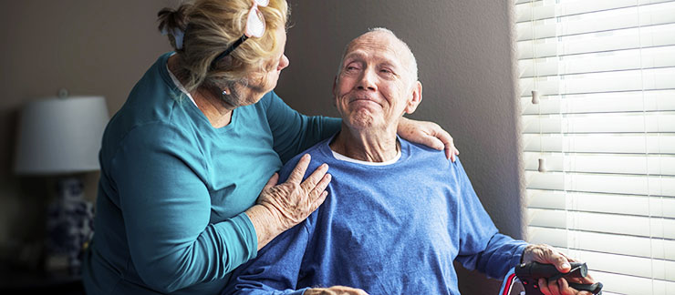 A caregiver comforts an elderly man with Lewy body dementia. 