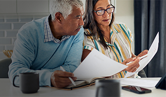 Senior couple holding financial documents at a table.