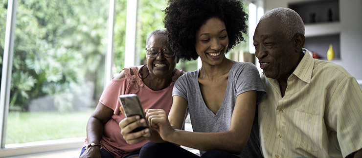 Female caregiver uses her phone to help smiling senior couple talk with family members. 