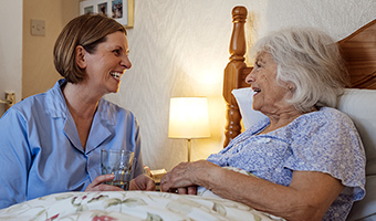 Elderly woman in bed is being cared for by a professional overnight care provider.