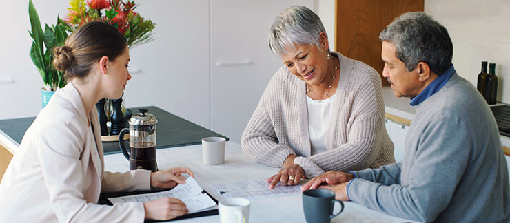 Senior couple fills out advanced directives in their home with a female lawyer.