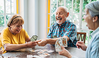 Group of happy seniors forming a social connection by playing cards at home.
