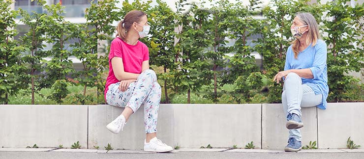 A woman with an elderly friend talking while social distancing during COVID-19