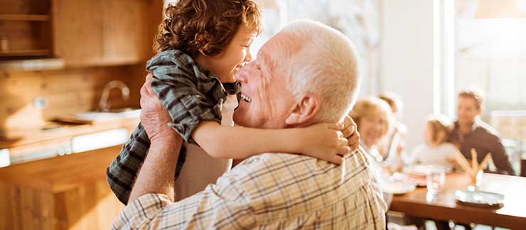 Elderly man picks up happy grandchild at home before Thanksgiving Day dinner.