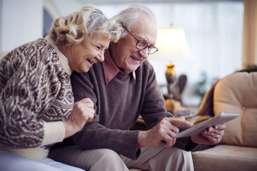 Happy elderly people spending time together at home, using gadgets