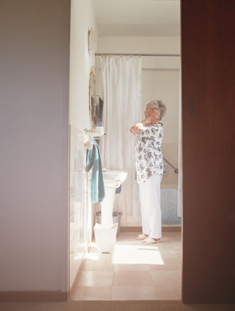 Elderly woman looking at herself in the bathroom mirror