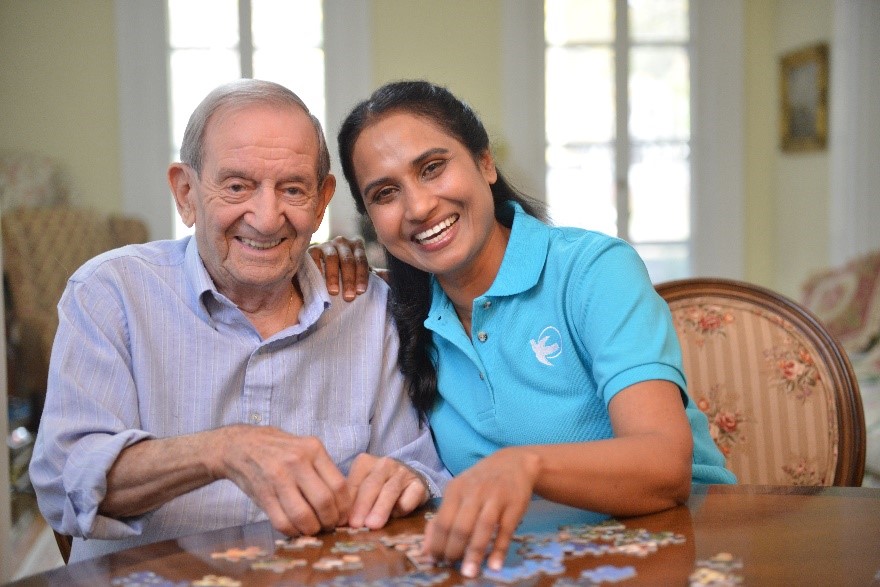 Visiting Angels caregiver and senior man solving a puzzle together