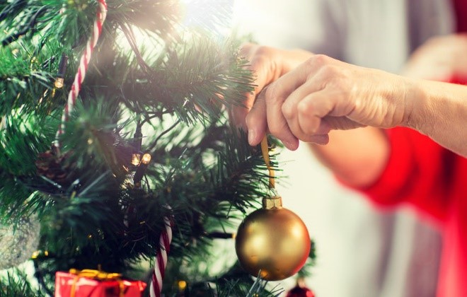 Putting an ornament on a Christmas tree