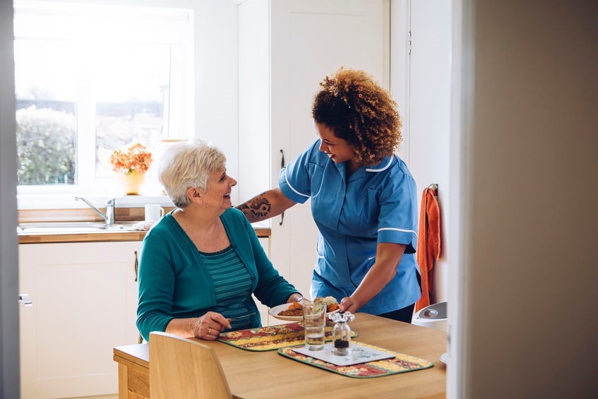 Caregiver assisting senior woman in the kitchen
