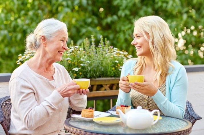 Adult daughter having tea with elderly mother