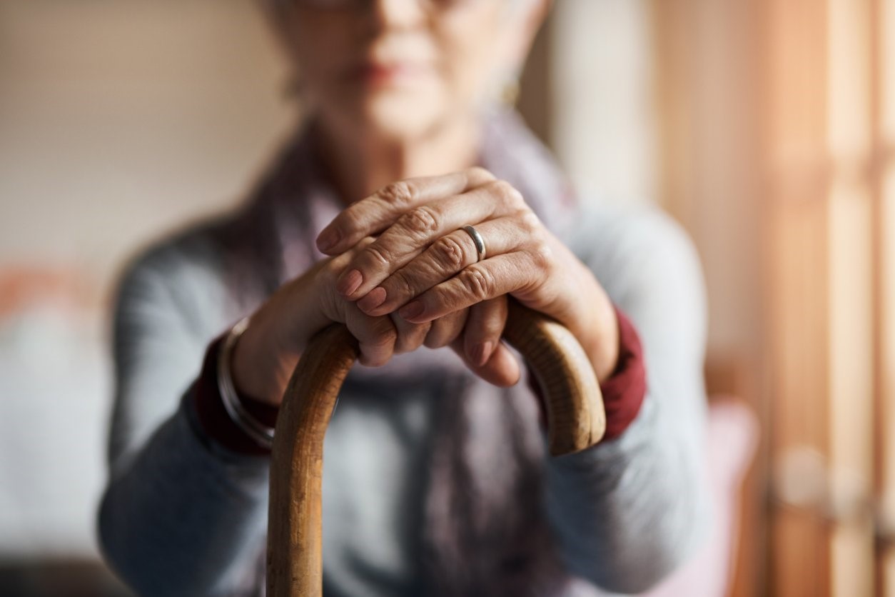 Senior woman resting her hands on a cane