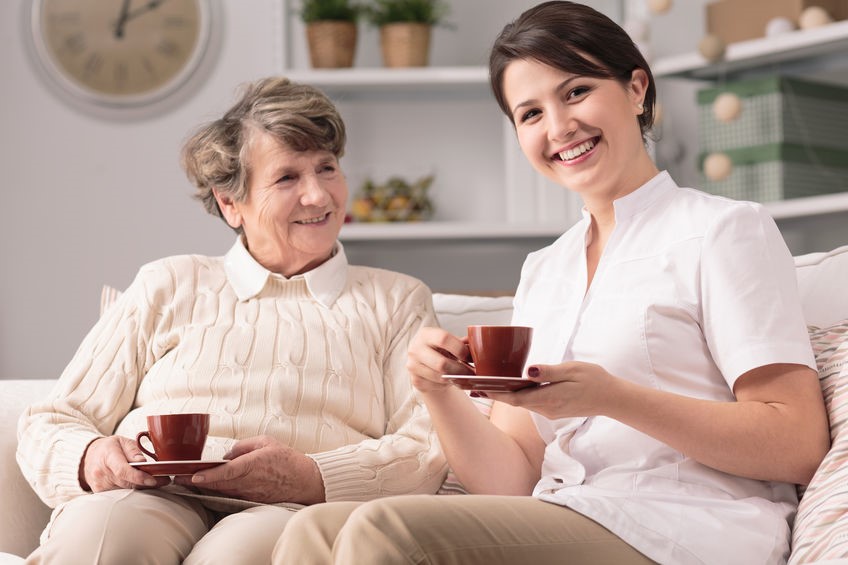In-home caretaker having tea with elderly woman