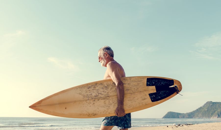 Senior man with surf board on beach