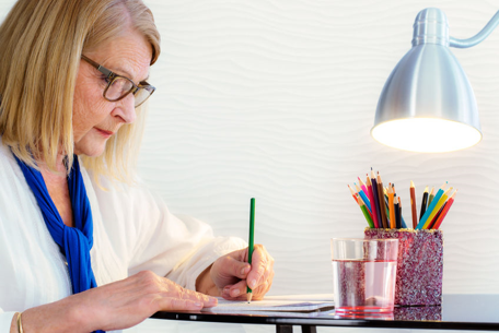 Senior woman coloring a book with colored penicls