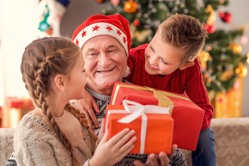 Grandfather opening christmas gifts with grandchildren