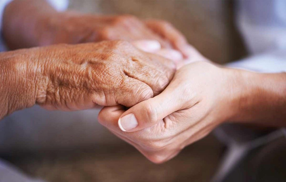home care aide holding hands of senior stroke survivor
