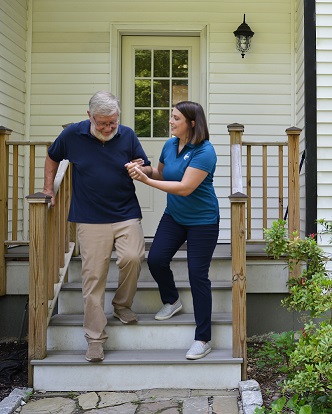 provider of companion care in Stamford assisting senior patient down stairs