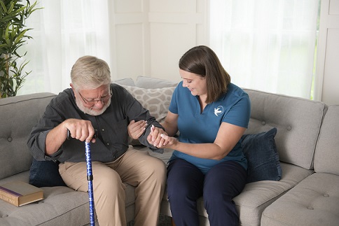 provider of home care in Renton assisting elderly patient on to couch