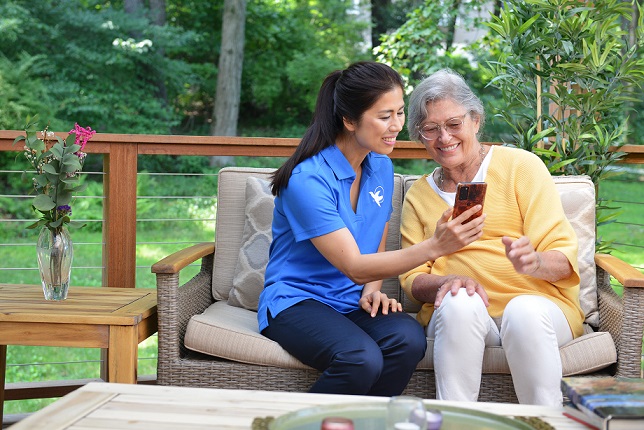 provider of in home care services in Albany, OR looking at photo on mobile phone with elderly patient