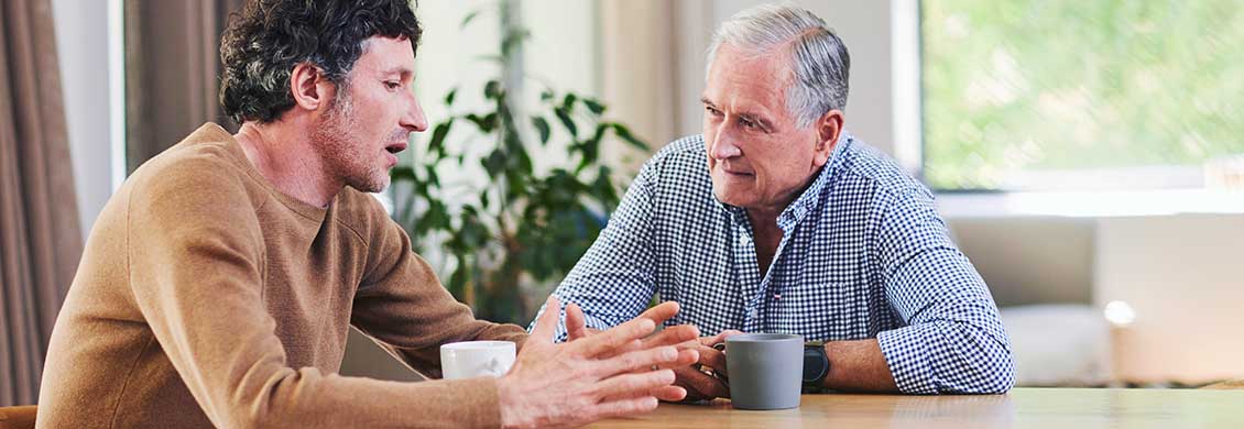 Mid-adult man discusses home care costs with father.