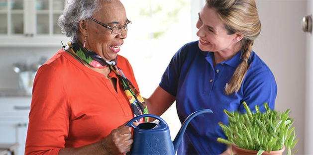 Caregiver and older women watering a plant