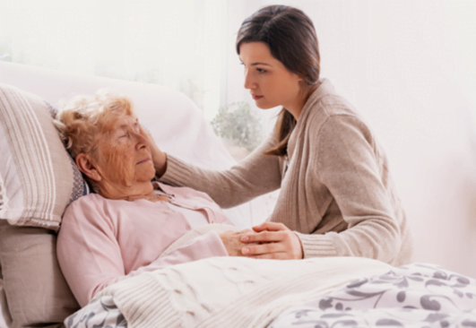 A caregiver sitting next to an elderly woman.