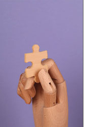 Wood hand holding a puzzle piece