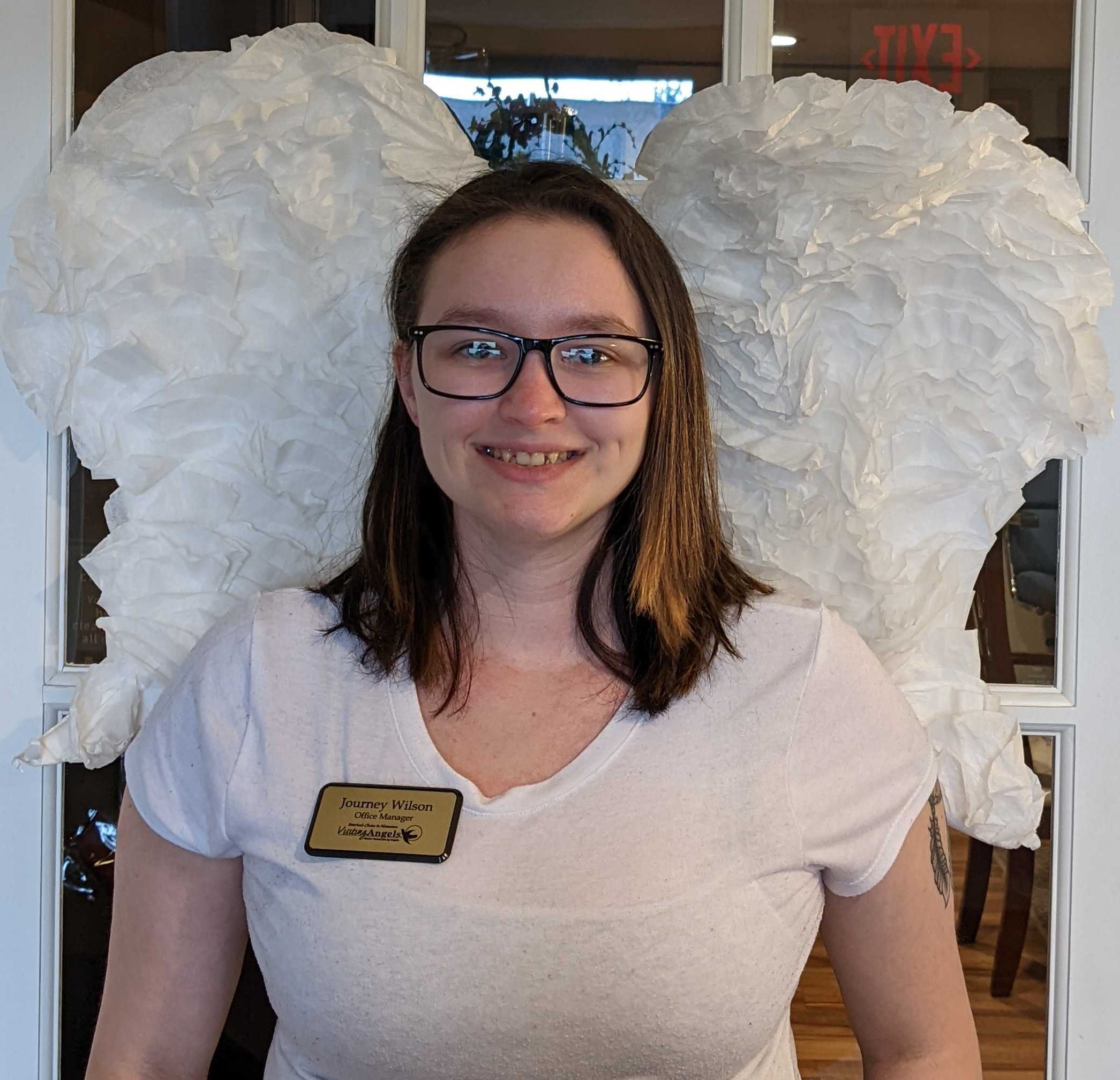 Journey Smith standing in front of Visiting Angels angel wings