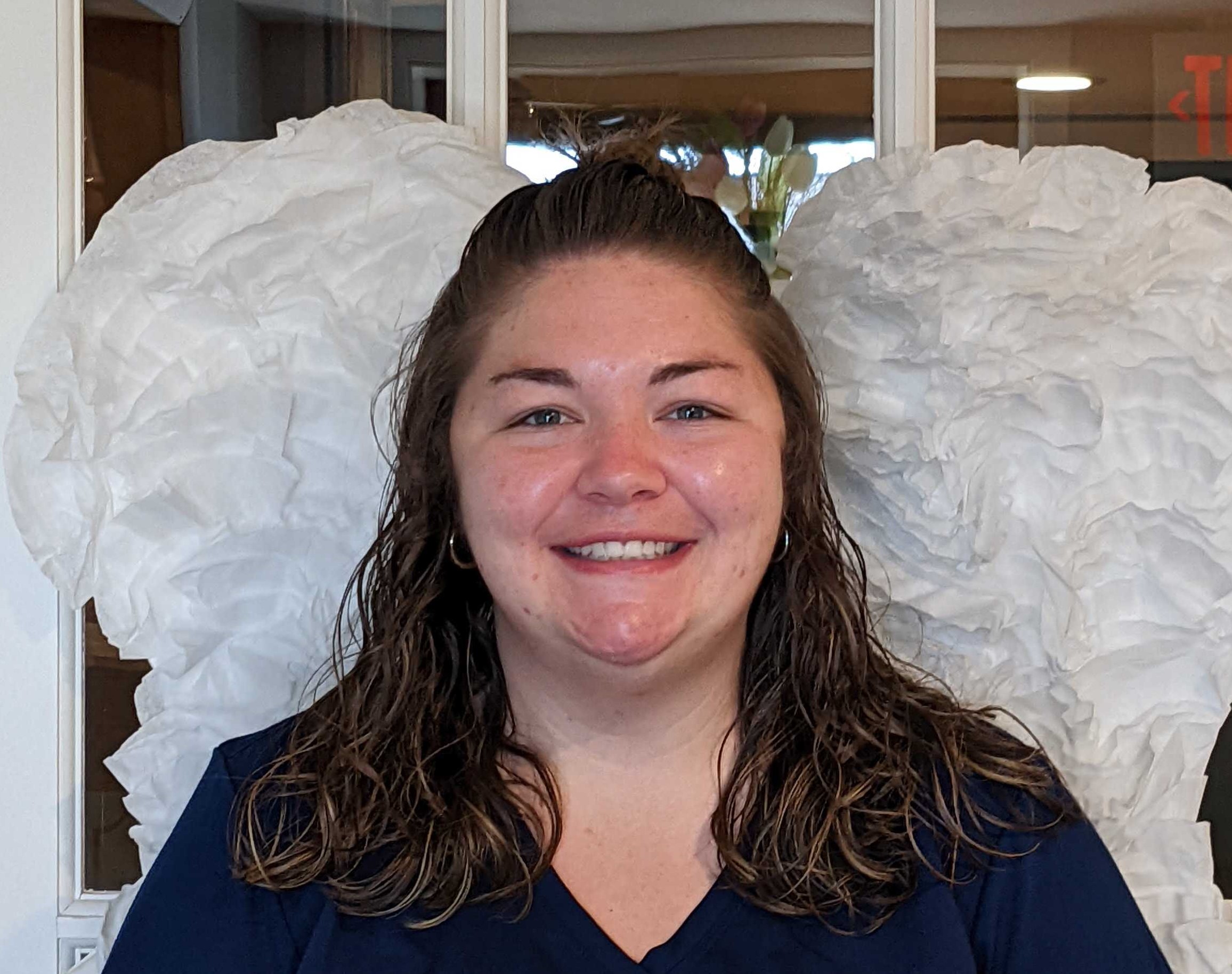 Keana standing in front of white angel wings