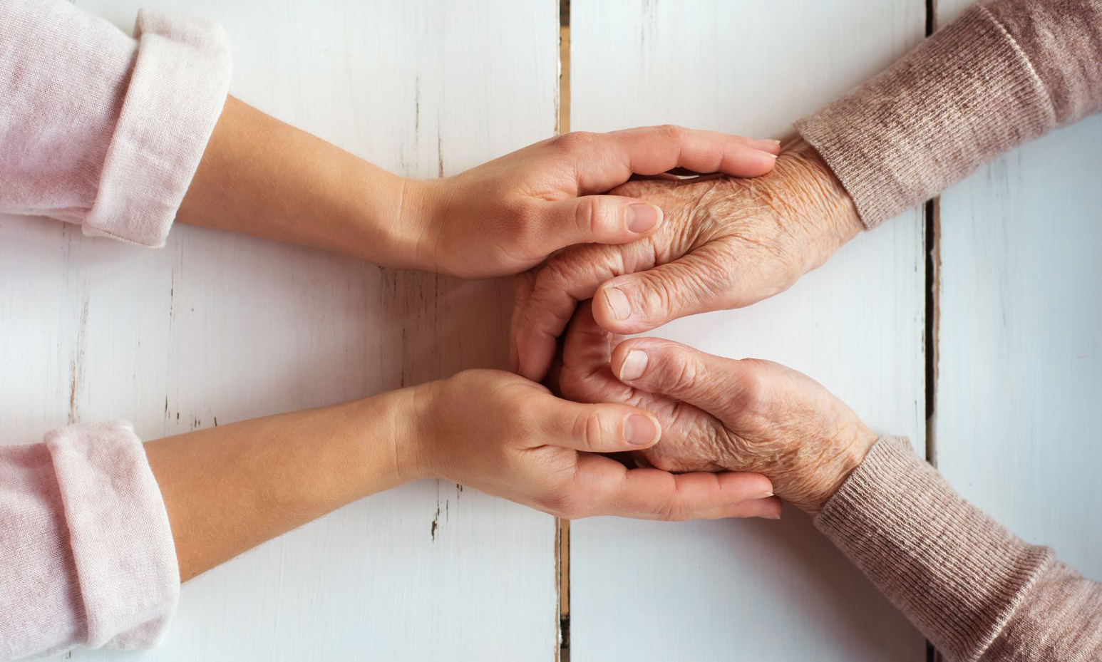 home caregiver holds the hands of client coping with Alzheimer's disease.
