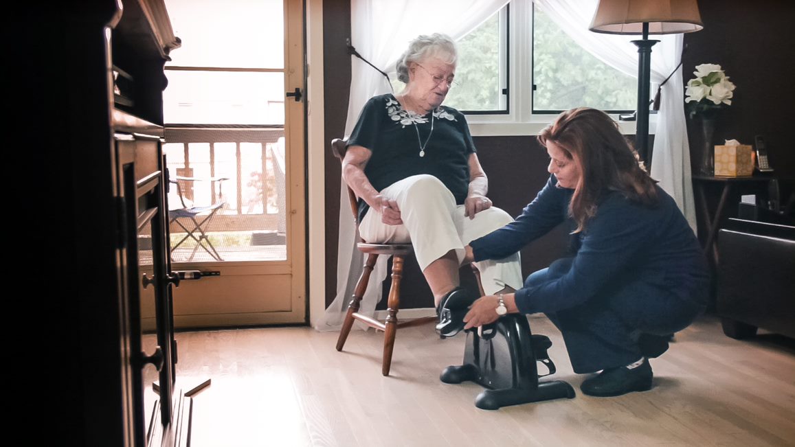 home caregiver helps senior exercise