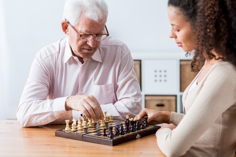 Companion care - home care aide playing chess with an elderly client
