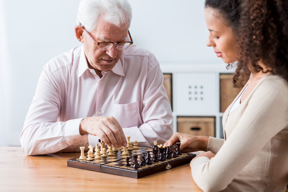 companion care - home care aide playing chess with an elderly client