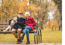 Couple sitting on park bench with dog
