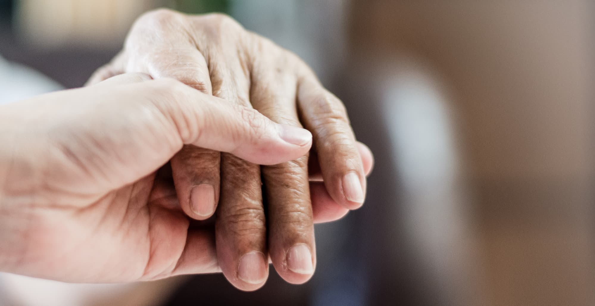 A nurses' hand holding the hand of an older patient